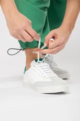 Zapatillas acordonadas de cuero color blanco con puntera de gamuza gris y detalles en verde.