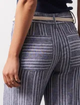 Pantalón de lino a rayas verticales en tonos azul, beige y blanco, con corte wide leg, pretina con pasadores, cierre y botón. Incluye cinturón de soga con hebilla redonda.
