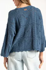 Sweater de tejido de punto calado color marrón, con diseño oversize, cuello redondo y mangas tres cuartos.