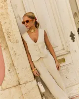 Pantalón de vestir color beige, de corte recto y talle alto, con pinzas frontales y cierre con cremallera, botón y gancho metálico.