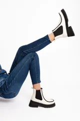 Botinetas de cuero vacuno color blanco tiza, con elásticos laterales negros, suela de goma antideslizante y plataforma con taco cuadrado.