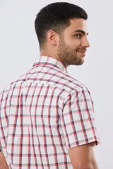 Camisa de manga corta a cuadros en tonos blanco, azul y gris, con cuello abotonado, bolsillo en el pecho y cierre frontal con botones.