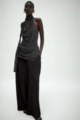 Top halter de viscosa con estampado de lunares, cuello halter, espalda descubierta y detalle de lazadas en el mismo tejido. Cuenta con bajo redondeado y cierre trasero con botones.