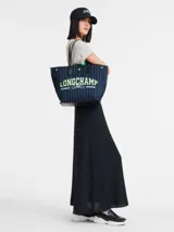 Bolso tote Longchamp modelo Essential, tamaño L. Diseño a rayas verticales en azul y blanco con logo de la marca en verde neón. Asas cortas de cuero negro y base rígida.