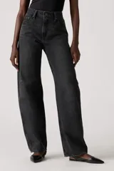 Pantalón de jean de corte baggy con diseño barrel, de tiro medio y color negro lavado. Presenta costuras laterales curvas que acentúan su silueta amplia y estructurada.