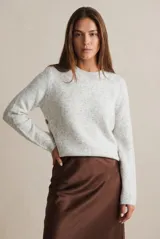 Sweater de punto gris melange con cuello redondo, manga larga y detalle de botones laterales en el costado.