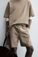 Bermuda de algodón color beige claro, corte relajado (relaxed fit), con cintura elástica ajustable mediante cordón y bolsillos laterales y trasero de plastrón.