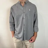 Camisa de manga larga gris con rayas verticales finas, cuello mao y bordado de un pato en el pecho.