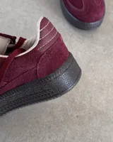 Zapatillas urbanas de cuero vacuno color negro, con suela alta y cordones.