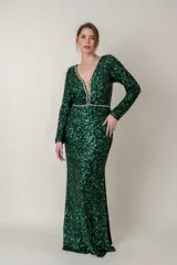 Vestido largo de fiesta confeccionado en tela con lentejuelas color verde esmeralda. Presenta escote en V profundo con detalle de tul transparente, mangas largas y apliques de strass en el escote y la cintura.