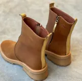 Botas de cuero color crema con cierre lateral y elástico en los laterales. Suela track color caramelo.