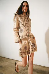 Chaqueta de hilatura de algodón en color beige, de cuello redondo y manga larga, con aplicaciones de bordados a contraste.