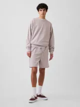 Short deportivo de felpa color gris claro, de corte holgado, con cintura elástica y cordón ajustable.