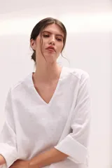 Blusa de lino color lila, de corte relajado y mangas largas amplias, con escote en V y ruedo curvo.