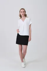Blusa de poliéster color blanco con cuello en V, mangas cortas con dobladillo y corte holgado.
