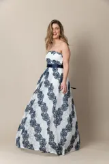 Vestido largo de fiesta blanco con encaje azul, corte strapless y lazo azul en la cintura.