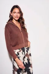 Campera tejida de algodón con cierre frontal completo y cuello alto. Presenta una textura acanalada vertical y puños y ruedo elásticos.