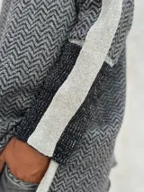 Sweater de punto con patrón de espiga en tonos beige y marrón, cuello alto, mangas largas con detalles en naranja y puños marrones.