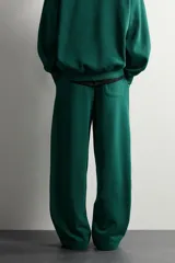Pantalón jogger de corte relajado y pernera ancha, confeccionado en tejido de algodón con interior perchado. Cuenta con cintura elástica ajustable mediante cordón interior, bolsillos laterales y un bolsillo trasero de plastrón.
