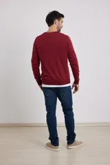 Suéter de punto color azul marino con cuello en V y manga larga. Se lleva sobre una remera blanca con cuello en V.