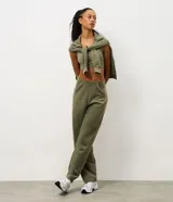 Pantalón deportivo de corte recto confeccionado en una mezcla de poliéster, modal y elastano. Presenta un diseño minimalista en color verde militar con bolsillos laterales integrados y cintura elástica.