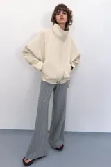 Chaqueta bomber oversize de efecto piel en color crema, con cuello subido, manga larga con hombro caído y cintura con frunces y cinturón ajustable con hebilla metálica. Cuenta con cierre frontal oculto y bolsillos laterales de vivo.
