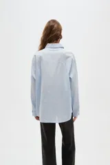 Camisa de algodón con estampado de rayas verticales finas, cuello camisero, cierre frontal con botones y bolsillos frontales tipo parche.