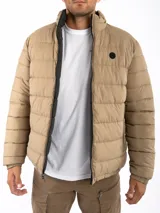 Campera puffer reversible color verde azulado con interior gris. Tiene cuello alto, cierre frontal y bolsillos laterales con cierre.