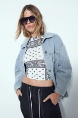 Top crop sin mangas color rojo con estampado tipo bandana en blanco y negro. Tiene cuello cerrado y sisas definidas.