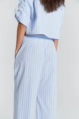 Pantalón recto de poplin de algodón rayado celeste y blanco, con elástico y tira de ajuste en la cintura, tajos laterales en el ruedo y detalles en poplin liso blanco.