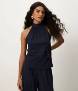 Blusa sin mangas color azul marino, con cuello alto y detalle de lazo integrado en el escote.