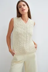 Chaleco de lana color crudo, tejido con escote en V y diseño con diferentes puntos combinados en el frente.