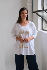 Remera blanca de corte holgado y manga larga, con estampado floral en color dorado en el frente.