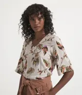 Blusa de viscosa color crudo con estampado de hojas coloridas, escote en V y mangas cortas.
