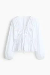 Blusa de popelina de algodón blanca, con escote en V pronunciado, cordones frontales para ajustar, mangas abullonadas y detalle de fruncidos.