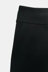 Bermudas de tiro medio y cintura ancha, color marrón, con bolsillos delanteros y cierre frontal con cremallera y ganchos metálicos.