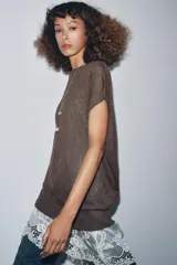 Vestido de punto marrón oscuro, sin mangas y cuello redondo, con un ruedo inferior de encaje blanco.