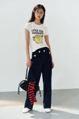 Camiseta de algodón flamé color blanco, de corte regular con cuello redondo y manga corta. Presenta un estampado frontal con texto y gráfico del personaje Little Miss Sunshine.