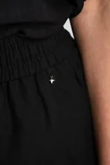 Short negro de lino con cintura elástica fruncida y cordón ajustable del mismo tono. Cuenta con bolsillos laterales.