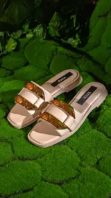 Sandalias chatas color beige con dos tiras anchas y hebillas doradas.