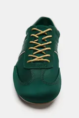 Zapatilla deportiva estilo running color verde, con combinación de materiales, pespuntes decorativos, cordones y talonera en contraste.