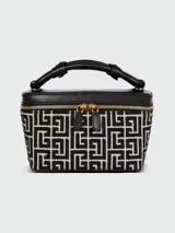 Vanity case de estructura rígida con diseño monogramado en blanco y negro. Presenta detalles en cuero negro, asa superior reforzada y cierre perimetral con herrajes dorados.