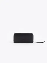 Maxi billetera de cuero vacuno con diseño matelassé en forma de V. Presenta un aplique metálico dorado en forma de labios en el frente y cierre perimetral con tirador de cuero.