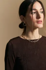 Top de manga larga con textura suave y leve brillo. Presenta una silueta al cuerpo, tajos laterales y terminaciones onduladas en el ruedo.