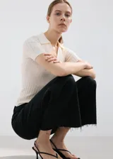 Pantalón de jean negro de corte recto y tiro alto, con diseño de pierna ancha y terminaciones deshilachadas en el ruedo.
