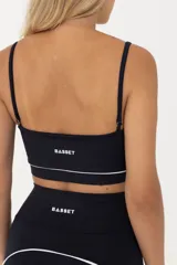 Top deportivo negro con breteles finos regulables y contorno inferior blanco.