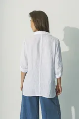 Camisa blanca de lino con cuello clásico, manga larga con puños abotonados y cierre frontal con botones. Corte recto y holgado.