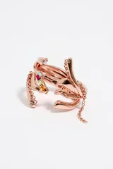 Pulsera ancha rígida de metal color oro rosado con diseño de manos entrelazadas adornadas con strass y gemas de colores.