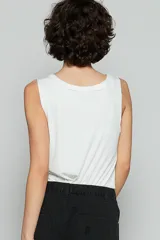 Musculosa negra con cuello en V, cierre de botones, banda en el cuello y botonadura con borde sin terminar, y bolsillo en el pecho.