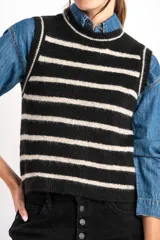 Chaleco de punto negro con rayas horizontales color crema, cuello alto y corte ajustado.
